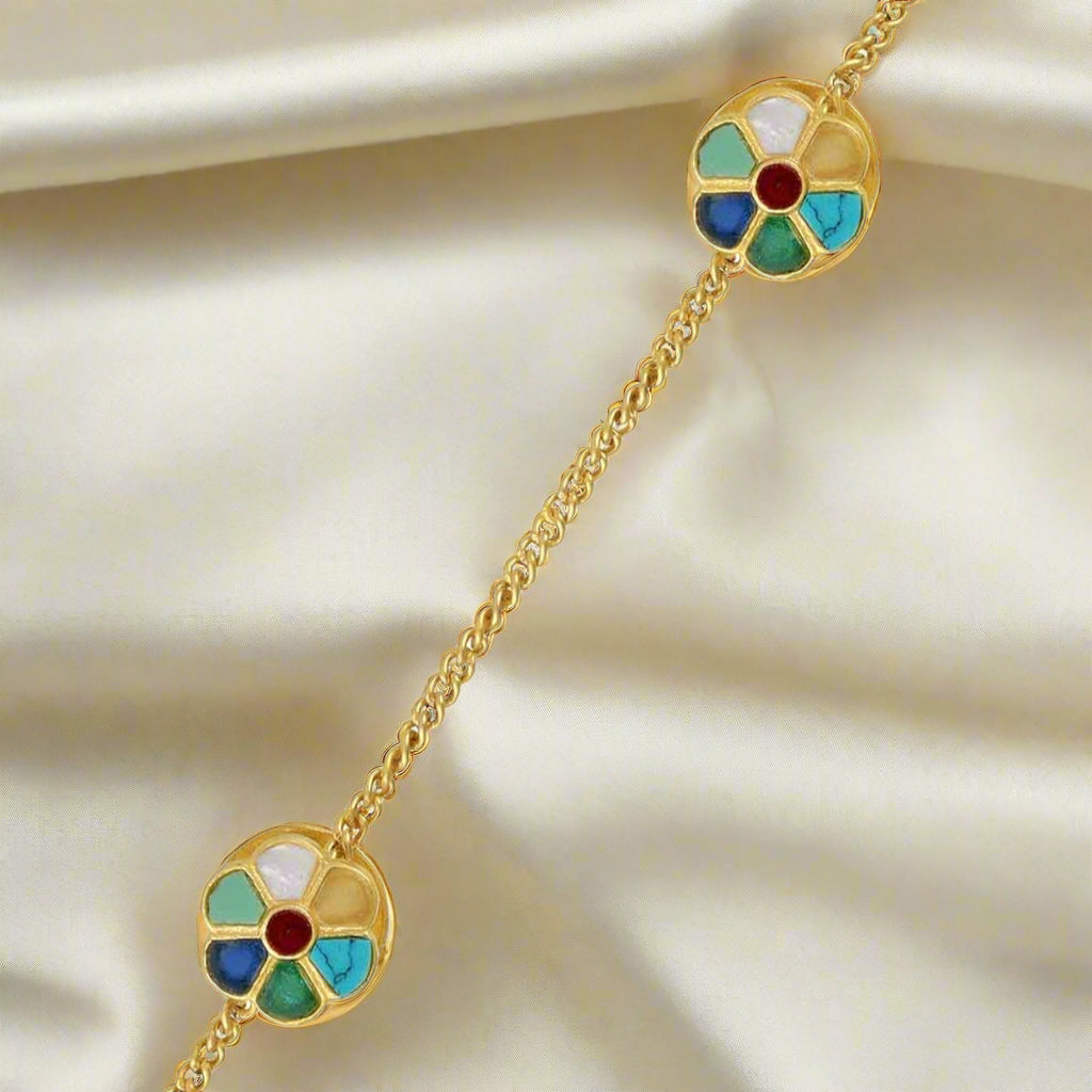 A pair of gold-colored metal buttons with multicolored floral patterns on a white background.